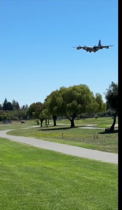 The airplane crosses the golfer's line of play.