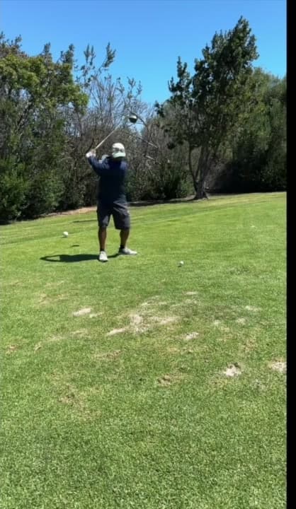 The golfer reaches the top of his backswing.