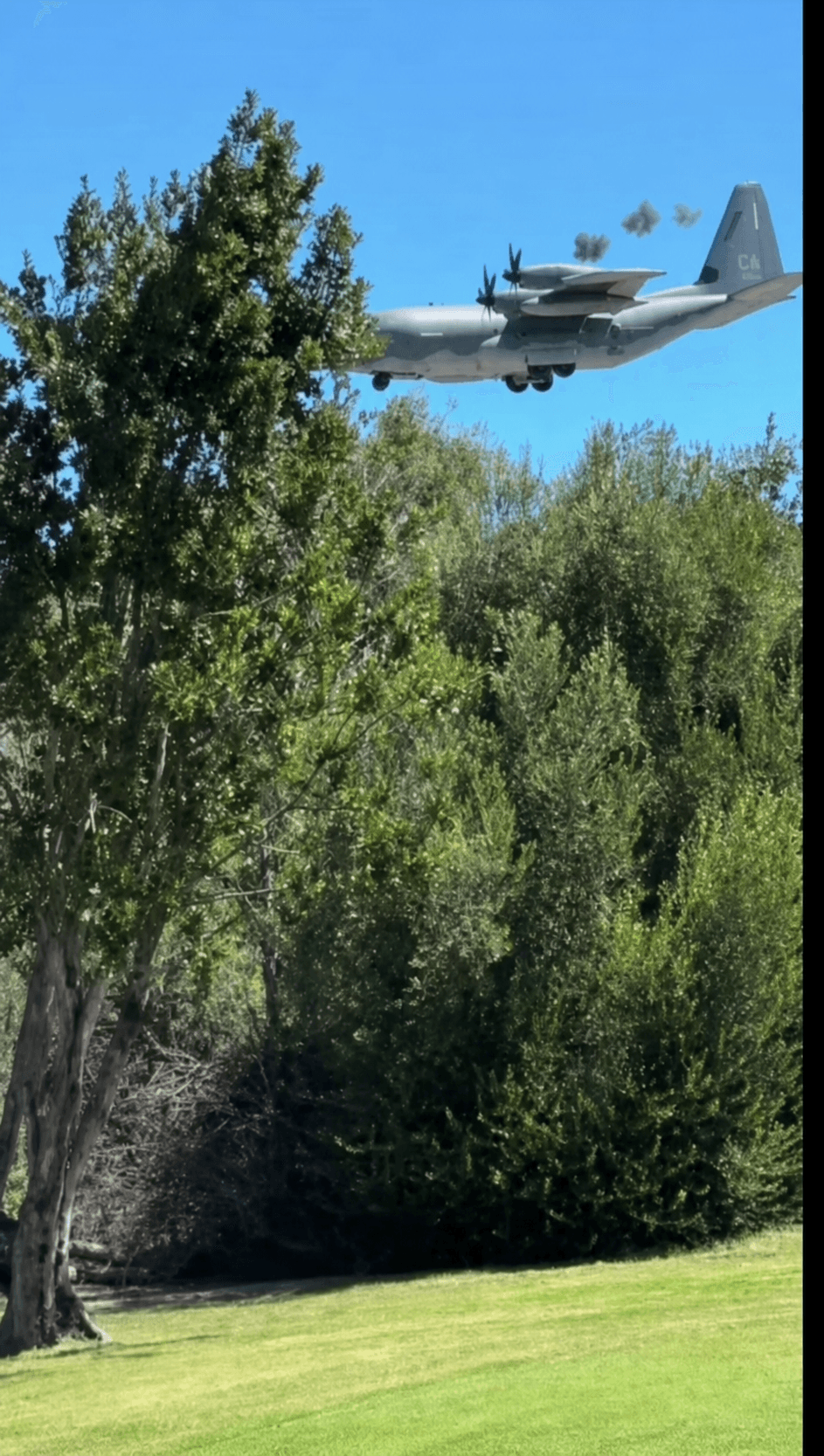 A low-flying airplane with smoke trailing from an engine.